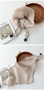 Detail of light beige cotton linen scarf with dark grey wavy edges and pompom tassel