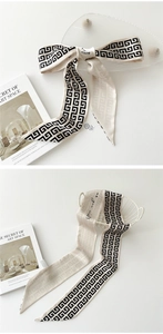 Détail de l'élégant foulard en soie crème avec motifs géométriques noirs et écriture