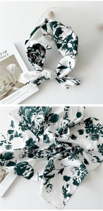 Gros plan d'un foulard carré en soie avec motifs floraux vert foncé sur tissu crème