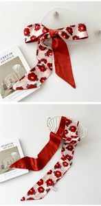 Détail du foulard en soie à motif camélia noué en nœud près d'un panier blanc