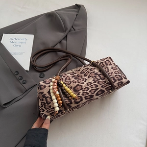 Detail of leopard print barrel bag featuring colorful wooden bead charm and brown handle