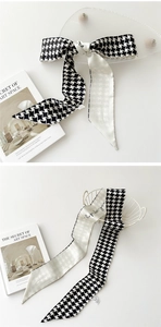 Détail d'un élégant foulard en soie étroit à motif d'étoiles noir et blanc noué avec style