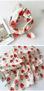 Détail d'un foulard carré en soie crème avec imprimés marguerites rouges et texture