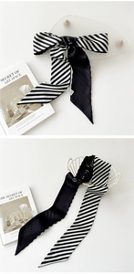 Gros plan d'un foulard en soie rayé noir et blanc noué en nœud sur une plaque