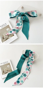 Détail d'un foulard en soie à fleurs et vert uni noué en nœud et posé dans un panier