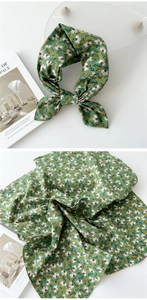 Détail d'un foulard en coton et lin vert avec motif floral délicat et bords finis