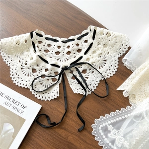 Col amovible chic en dentelle blanche avec nœud en ruban noir sur fond de bois