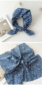 Détail d'un foulard en coton et lin bleu marine à fleurs noué en bandeau chic