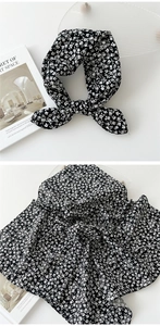 Détail d'un foulard en coton et lin à fleurs noir et blanc noué en nœud sur fond blanc