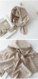 Détail d'un foulard en coton et lin à fleurs sur un plateau en verre avec accessoires