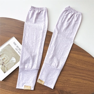 Dettaglio di manicotti in pizzo lilla con texture jacquard ed etichetta su legno