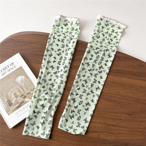 Detail of mint green sun protection sleeves with black butterfly print on wooden surface