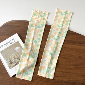 Detail of breathable ice silk sun sleeves with yellow banana patterns on a wooden tray