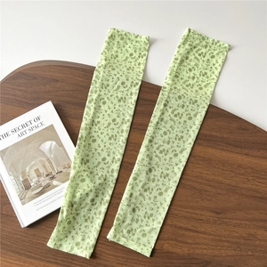 Detail of light green floral mesh sun sleeves on a wooden tray with a minimalist book