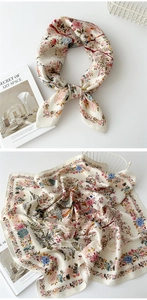 Detail of floral and bird print square scarf on white book and iron basket