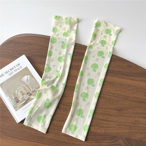 Detail of breathable ice silk sun sleeves with cute green apple patterns on wooden surface
