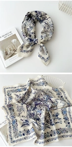 Detail view of the silk scarf featuring a blue-purple floral bird print and smooth texture