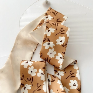Petit foulard en soie marron à motif floral et ruban pour cheveux sur fond texturé blanc