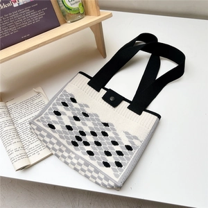Detail of the thick knit texture and secure metal snap closure on the geometric tote bag