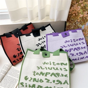 Chic knitted tote bags with monogram patterns in four colors on a sunlit window sill