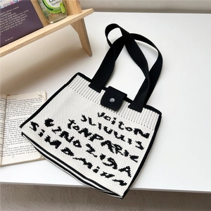Close-up of knit tote bag with black letter patterns and silver snap button closure