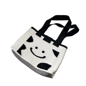 Minimalist knitted tote bag with black and white smile pattern and geometric color blocks