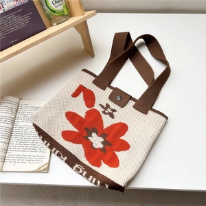 Close-up of knitted tote bag with orange floral patterns and button strap closure
