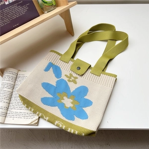 Close-up of floral knitted tote bag featuring a green strap and button closure detail