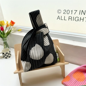 Close-up of thick knitted knot bag with black and white floral jacquard pattern