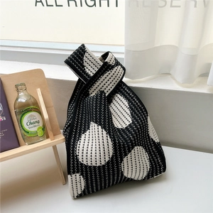 Detailed view of black and white knitted tote bag with geometric drop patterns and knot handle