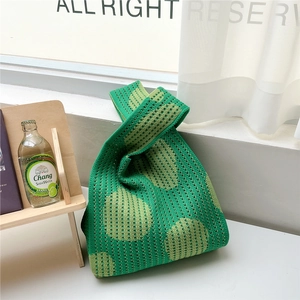 Detailed close-up of green knit bucket bag featuring hollow pattern and knot handle design