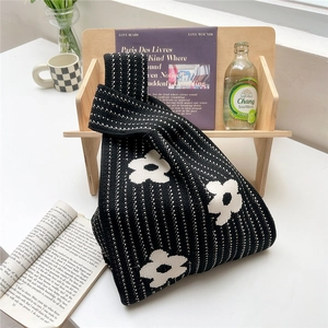 Close-up of knit tote bag featuring white floral patterns and vertical polka dot stripes