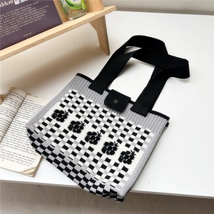 Detail of checkered knit tote bag with floral patterns and metal snap closure