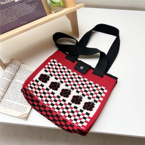Close-up of knitted tote bag featuring a red and black checkerboard pattern with sun flower