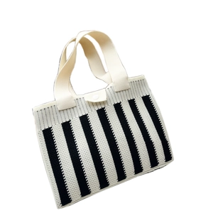 Vertical black and white striped knitted tote bag with cream handles and button closure
