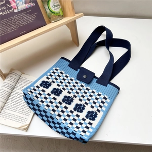 Close-up of blue and white checkered knit tote bag with floral patterns and snap closure