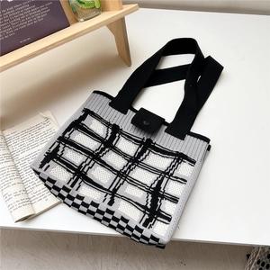 Dettaglio di una borsa tote in maglia a scacchi bianchi e neri con chiusura a bottone