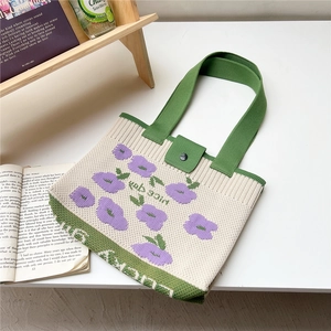 Close-up of knit tote bag featuring purple floral patterns and Nice day text detail