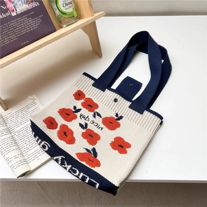 Detail of flower knit tote bag featuring red poppy pattern and lucky lettering
