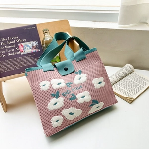 Detail of knitted floral tote bag with green handles and round snap button closure