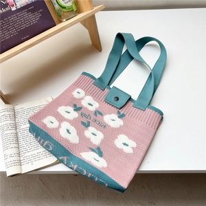 Close-up of knit tote bag with floral pattern, magnetic snap closure and KAB GIRL text