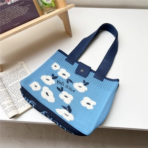 Detail shot of blue floral knit tote bag showing yarn texture and button closure