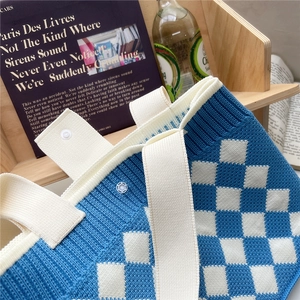 Blue and white checkered knitted tote bag with woven texture and button closure