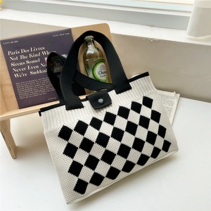 Knitted checkerboard tote bag with black strap and buckle in a lifestyle setting