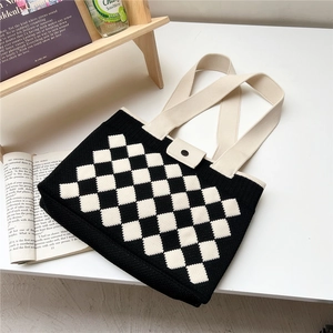 Detail of checkered knit tote bag showing black and white diamond texture and top button