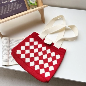 Close-up of red and white checkered knit tote bag with thick weave texture and wide handle