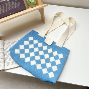 Close-up of blue and white checkered knit tote bag with button closure and wide strap