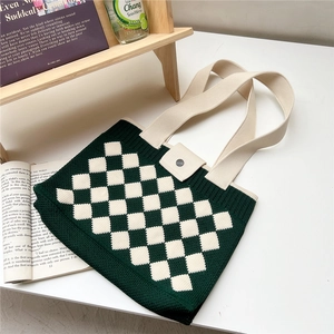 Detail of green and white checkerboard knit tote bag with metal button closure and strap