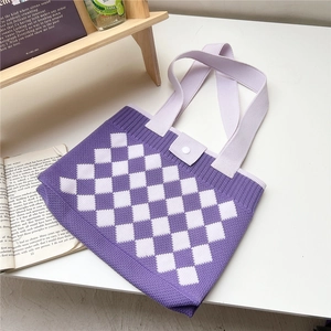 Detail of purple checkered knit tote bag with button closure on a cozy wooden desk