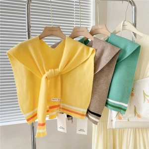 Detail view of knitted shawls in ginger, camel and green with striped border accents